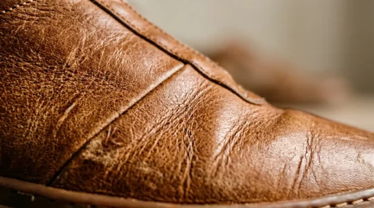 Gros plan sur le cuir pleine fleur d'une sneaker haut de gamme montrant la texture naturelle et les marques authentiques