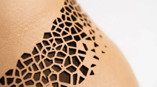 Vue macro d'une découpe laser haute précision sur cuir de sneaker avec motifs géométriques complexes