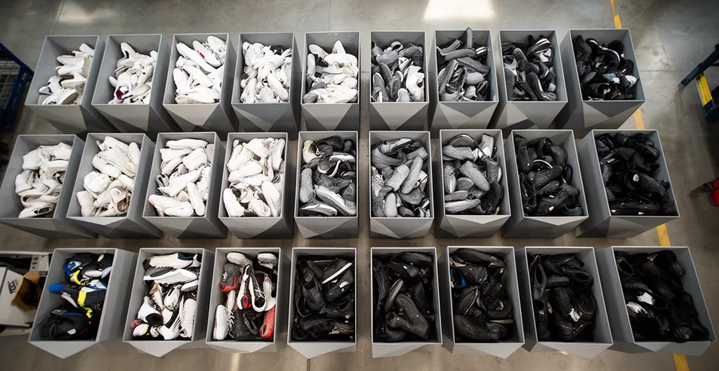 Vue en plongée de baskets usagées triées par couleur dans des bacs de collecte textile