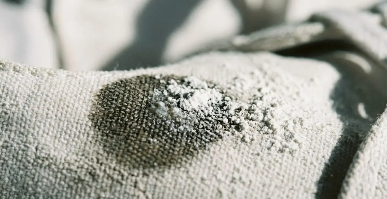 Vue macro d'une poudre blanche absorbante appliquée sur une tache de gras sur basket blanche